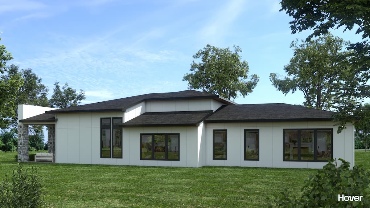 Contemporary white house with large windows and a sloped roof in a lush green setting.