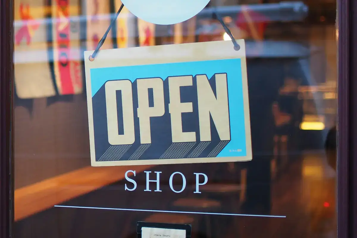 Open sign hanging in a shop window, inviting customers inside.
